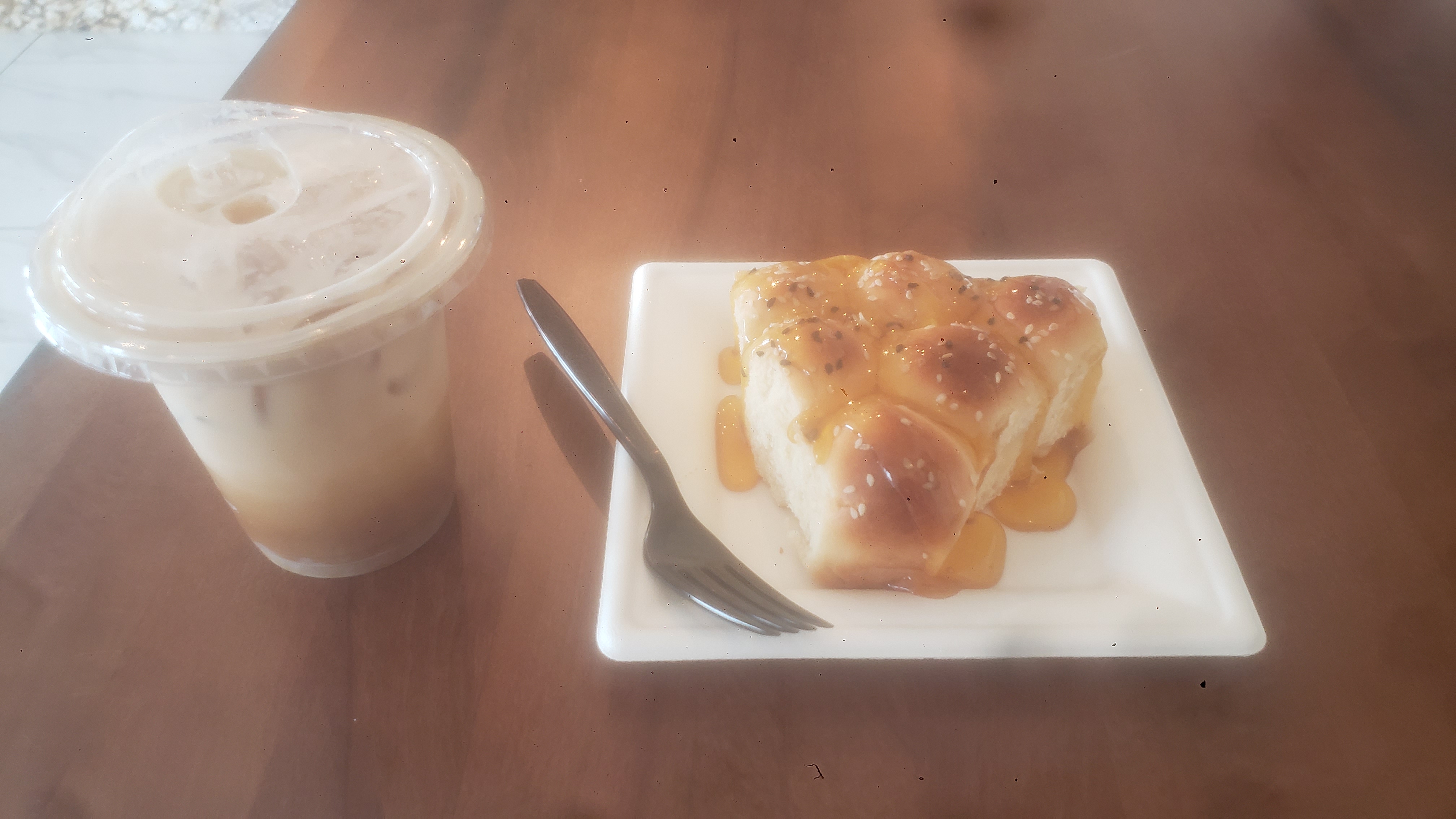 Khaliat nahl on a paper plate with a fork and plastic cup of iced coffee next to it. 